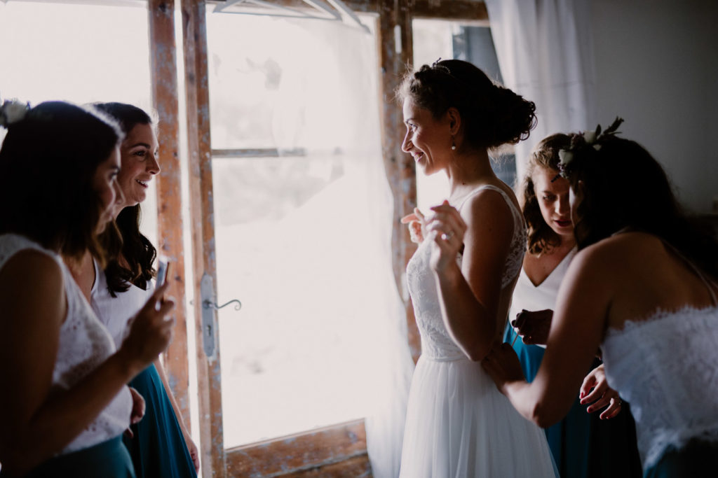 la mariée enfile sa robe après sa préparation pour son mariage au moulin des gaffins en provence