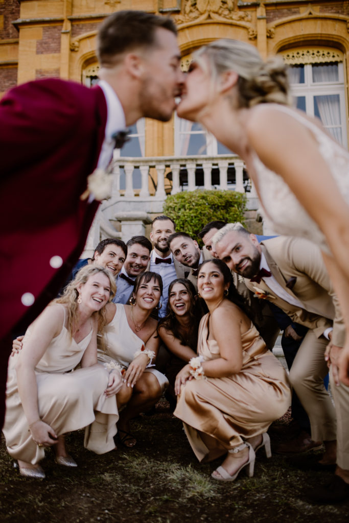 Groupe d'amis qui regardent les mariés s'embrasser lors d'un mariage au château de la Flachère
